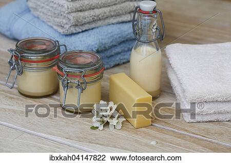 Stock Image - Soap piece with terry towels, body lotion in jars, flower. Fotosearch