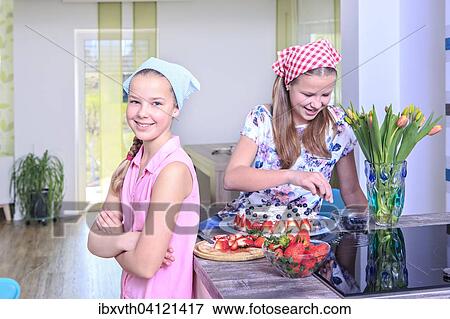 Stock Photo - Teenage girls baking a cake at home with fresh fruit. Fotosearch