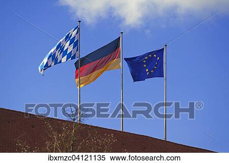 Stock Photography - Three waving flags of Bavaria, Germany and Europe on a roof, Regensburg, Upper Palatinate, Bavaria, Germany, Europe. Fotosearch