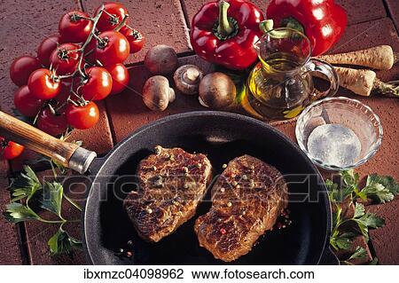 Two fried pepper steaks in a pan, decoration with fresh tomatoes, mushrooms, celeriac and red peppers, on terracotta tiles View Large Photo Image Stock Image - Two fried pepper steaks in a pan, decoration with fresh tomatoes, mushrooms, celeriac and red peppers, on terracotta tiles. Fotosearch