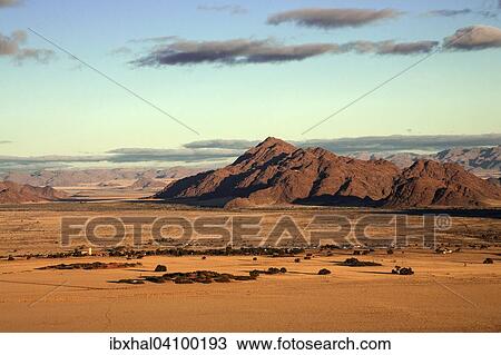 Stock Image - View from Elim Dune onto grass steppe, Sesriem Camp and Tsaris Mountains, Namib Desert, Namib Naukluft Park, Namibia, Africa. Fotosearch