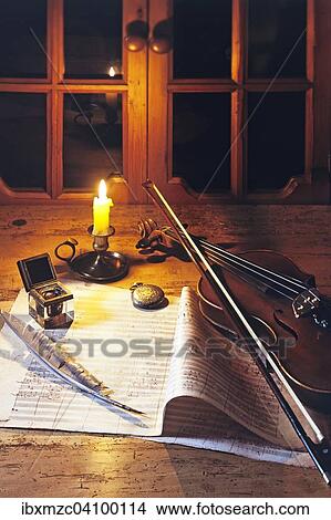 Violin on a music sheet with inkwell and quill, illuminated by a candle View Large Photo Image Picture - Violin on a music sheet with inkwell and quill, illuminated by a candle. Fotosearch