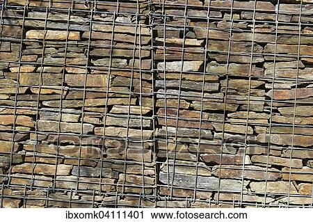 Wall with stacked stones behind steel mesh View Large Photo Image Stock Image - Wall with stacked stones behind steel mesh. Fotosearch