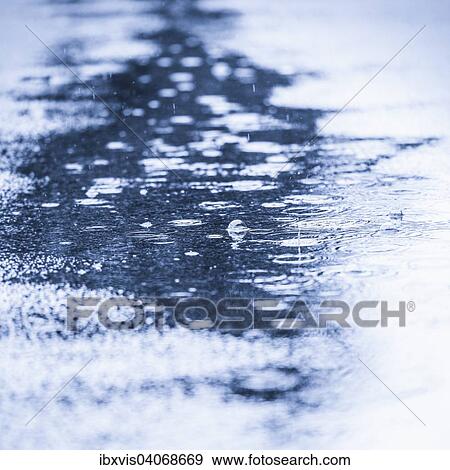 Water puddle with rain drops falling View Large Photo Image Stock Photo - Water puddle with rain drops falling. Fotosearch