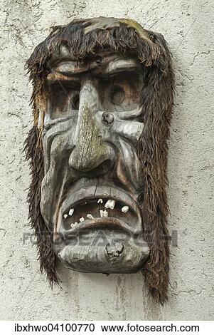 Stock Image - Wooden mask hanging on a wall, carved, Alps, Ernen, Valais, Switzerland, Europe. Fotosearch