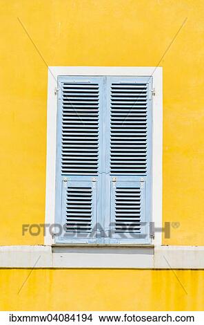 Picture - Yellow plastered wall with closed bright blue wooden shutters, Corsica, France, Europe. Fotosearch