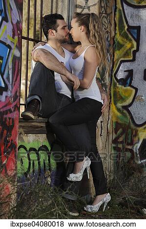 Young couple kissing against a barred window in a ruined building covered in graffiti View Large Photo Image Stock Photo - Young couple kissing against a barred window in a ruined building covered in graffiti. Fotosearch