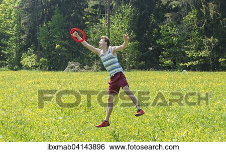 Young man catching frisbee in meadow, Perlacher Forst, Munich, Bavaria, Germany, Europe View Large Photo Image Stock Photograph - Young man catching frisbee in meadow, Perlacher Forst, Munich, Bavaria, Germany, Europe. Fotosearch