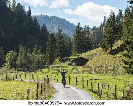 Picture - Young man riding a bicycle without his hands, mountain landscape, Valepptal, Spitzingsee, Bavaria, Germany, Europe. Fotosearch