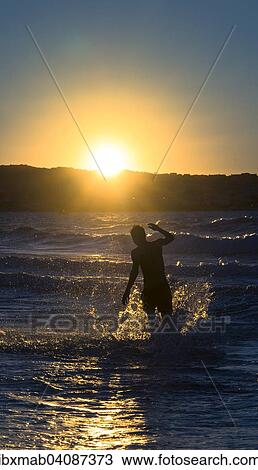 Stock Image - Young man, silhouette, jumping in the water at sunset, sunset by the sea, Haute-Corse, Corsica, France, Europe. Fotosearch