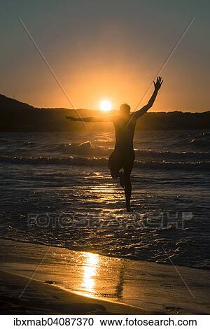 Stock Image - Young man, silhouette, jumping on the beach at sunset, sunset by the sea, Haute-Corse, Corsica, France, Europe. Fotosearch