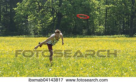 Young man throwing frisbee in meadow, Perlacher Forst, Munich, Bavaria, Germany, Europe View Large Photo Image Stock Photo - Young man throwing frisbee in meadow, Perlacher Forst, Munich, Bavaria, Germany, Europe. Fotosearch