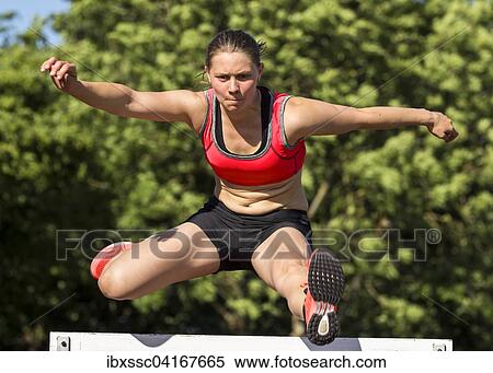 Young woman, 20 years, hurdling View Large Photo Image Stock Photography - Young woman, 20 years, hurdling. Fotosearch