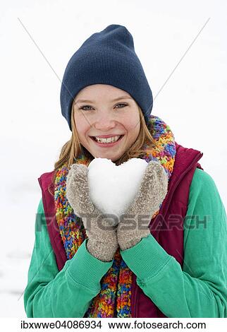 Young woman, 22 years, holding a heart made of snow View Large Photo Image Picture - Young woman, 22 years, holding a heart made of snow. Fotosearch