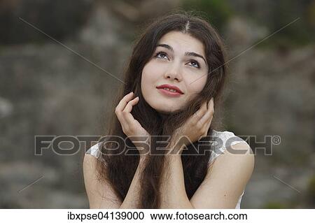 Stock Image - Young woman with long brown hair, misty-eyed. Fotosearch