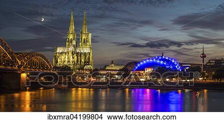 Picture - City-panorama of Cologne at dusk, Rhine, Hohenzollern Bridge, cathedral, the Musical Dome, Colonius TV tower, rising moon behind, Cologne, North Rhine-Westphalia, Germany, Europe. Fotosearch