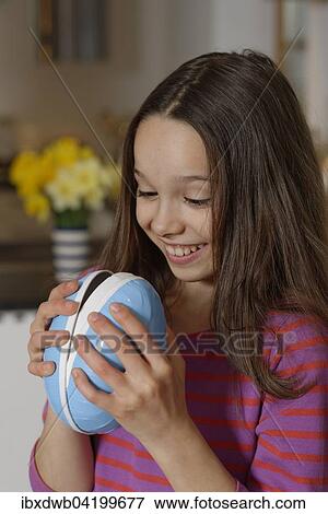 Girl looking curiously into a large Easter egg, Easter gift, Upper Bavaria, Bavaria, Germany, Europe View Large Photo Image Stock Photo - Girl looking curiously into a large Easter egg, Easter gift, Upper Bavaria, Bavaria, Germany, Europe. Fotosearch