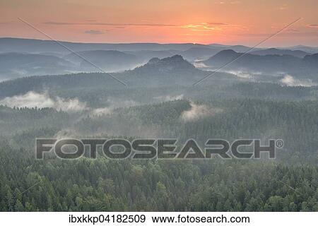 Stock Photo - Mist rising from the forest, in the morning, at sunrise, Saxon Switzerland, Elbe Sandstone Mountains, Saxony, Germany, Europe. Fotosearch