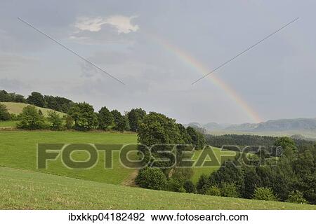 Stock Image - Rainbow and landscape of Saxon Switzerland in Sebnitz, Elbe Sandstone Mountains, Saxony, Germany, Europe. Fotosearch