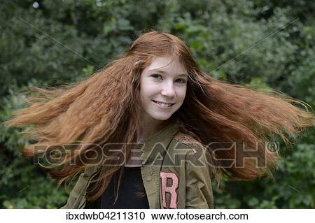 Stock Image - Teenage girl with long red hair, flicking her hair, Germany, Europe. Fotosearch