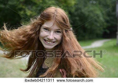 Stock Image - Teenage girl with long red hair, flicking her hair, Germany, Europe. Fotosearch