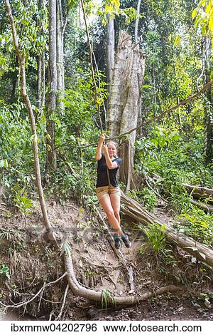 Young Woman Swinging On A Vine In The Jungle Tropical Rain Forest Taman Negara Malaysia Asia Stock Photograph