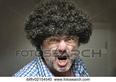 Stock Image - Angry man wearing a wig screaming with his mouth wide open. Fotosearch