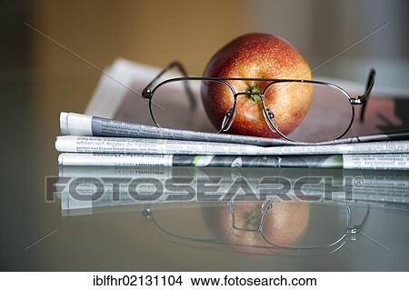 Apple, newspaper and glasses lying on a glass table View Large Photo Image Picture - Apple, newspaper and glasses lying on a glass table. Fotosearch