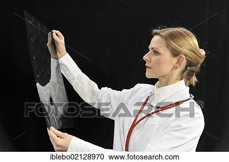 Stock Image - Assistant physician, young doctor looking at an X-ray. Fotosearch