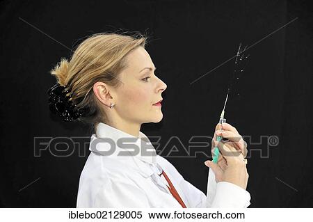 Stock Photography - Assistant physician, young doctor preparing a syringe. Fotosearch