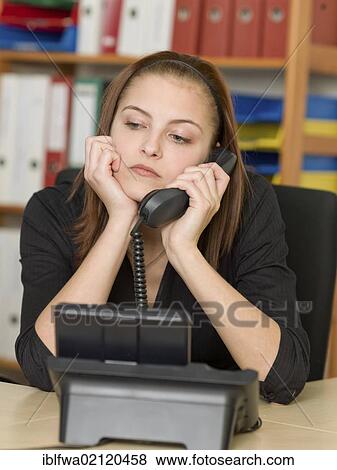 Stock Photo - Bored female office worker making a telephone call. Fotosearch
