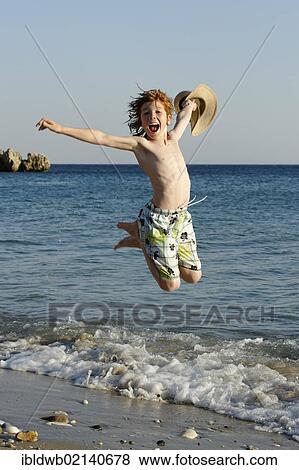 Boy jumping for joy on a beach by the sea View Large Photo Image Stock Photo - Boy jumping for joy on a beach by the sea. Fotosearch