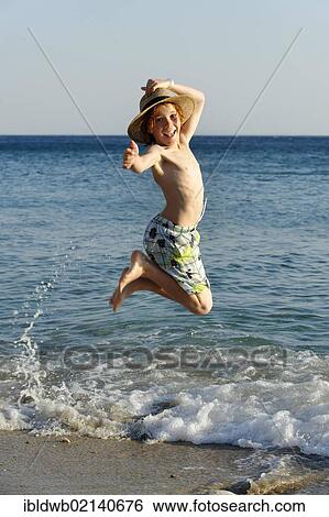 Boy jumping for joy on a beach by the sea View Large Photo Image Stock Photograph - Boy jumping for joy on a beach by the sea. Fotosearch