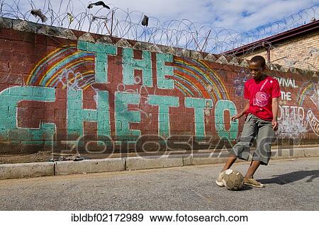 Boy playing football in front of wall with the word "The Ghetto", Soweto Township, Gauteng, South Africa, Africa View Large Photo Image Stock Photo - Boy playing football in front of wall with the word "The Ghetto", Soweto Township, Gauteng, South Africa, Africa. Fotosearch