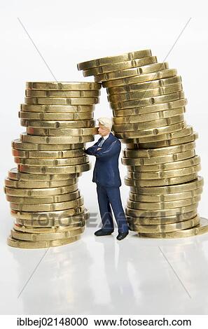 Businessman, figurine, between stacks of coins View Large Photo Image Stock Image - Businessman, figurine, between stacks of coins. Fotosearch