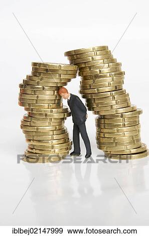 Businessman, figurine, between stacks of coins View Large Photo Image Stock Photo - Businessman, figurine, between stacks of coins. Fotosearch