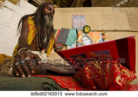 Stock Image - Chanting Sadhu reciting from the holy books at the ghats of Varanasi in the morning, Uttar Pradesh, India, Asia. Fotosearch