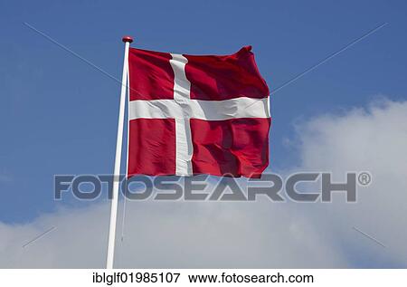 Stock Photo - Danish national flag against a blue sky with clouds, Saeby, North Jutland region, Denmark, Europe. Fotosearch