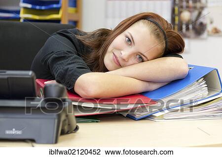 Stock Image - Exhausted office worker resting head on files and folders. Fotosearch