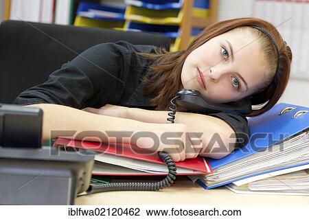 Stock Image - Exhausted office worker resting head on files and folders. Fotosearch