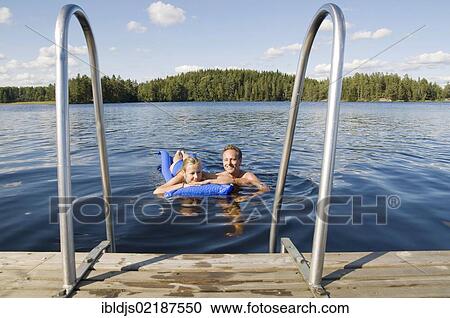 Stock Image - Father and daughter swimming in a lake near Bengtsfors, Dalsland, Sweden, Europe. Fotosearch