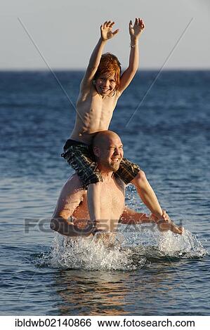 Father and son splashing around in the sea View Large Photo Image Stock Photograph - Father and son splashing around in the sea. Fotosearch