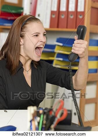 Female office worker shouting into telephone View Large Photo Image Stock Photo - Female office worker shouting into telephone. Fotosearch