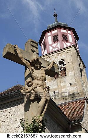 Stock Photo - Figure of Christ on the cross, half-timbered tower of the Romanesque church of St. Johann at back, Schwaebisch Hall, Baden-Wuerttemberg, Germany, Europe. Fotosearch