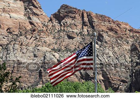 Stock Photograph - Flag of the United States flying in front of rock formations in the Zion National Park, Utah, USA, North America. Fotosearch