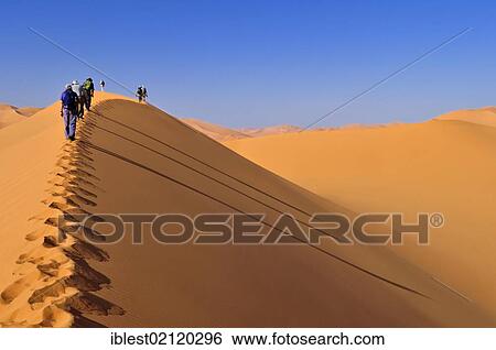 Stock Photograph - Group of tourists hiking through the sand dunes of Erg Mehejibad, Ahnet, Algeria, Sahara, North Africa, Africa. Fotosearch