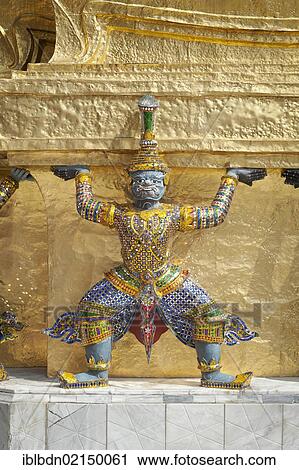 Stock Image - Guardian statue on the base of a golden chedi at Wat Phra Kaeo, Wat Phra Kaew, the Royal Grand Palace, Bangkok, Thailand, Asia. Fotosearch