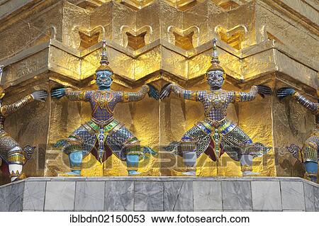 Stock Image - Guardian statues on the base of a golden chedi at Wat Phra Kaeo, Wat Phra Kaew, the Royal Grand Palace, Bangkok, Thailand, Asia. Fotosearch