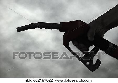 Hand holding a petrol pump nozzle silhouetted against a dark cloudy sky View Large Photo Image Stock Image - Hand holding a petrol pump nozzle silhouetted against a dark cloudy sky. Fotosearch
