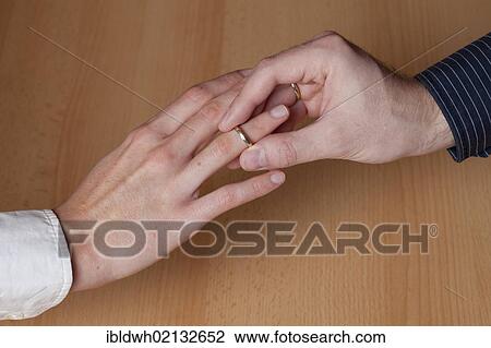 Hands of a young couple getting married, young man, 23, slipping a wedding ring on the hand of a young woman, 27 View Large Photo Image Stock Image - Hands of a young couple getting married, young man, 23, slipping a wedding ring on the hand of a young woman, 27. Fotosearch